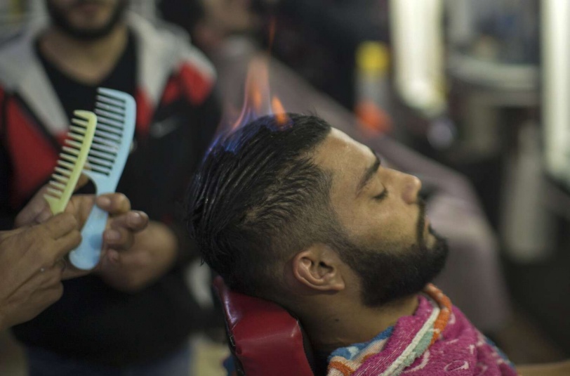 صور.. لماذا يستخدم هذا الحلاق الفلسطيني النار فوق رؤوس زبائنه؟
